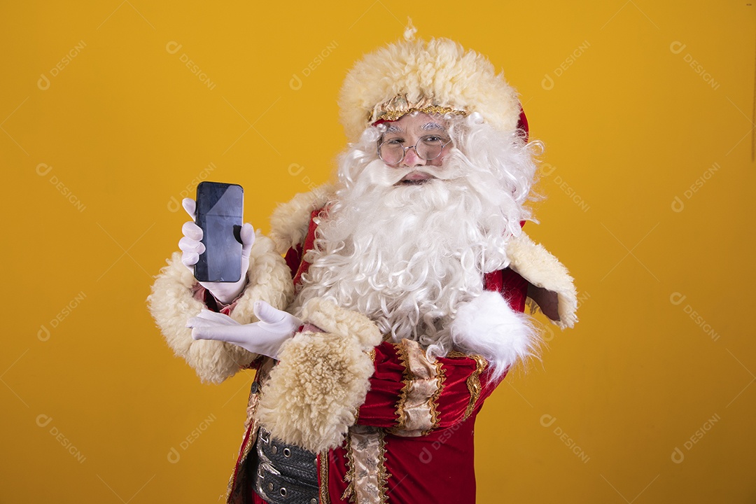 Papai Noel feliz e sorridente segurando celular smartphone Feliz Natal