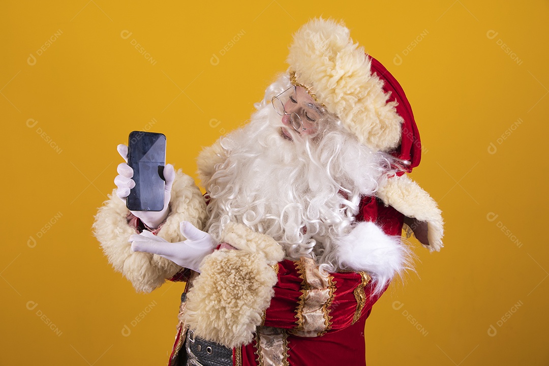 Papai Noel feliz e sorridente segurando celular smartphone Feliz Natal