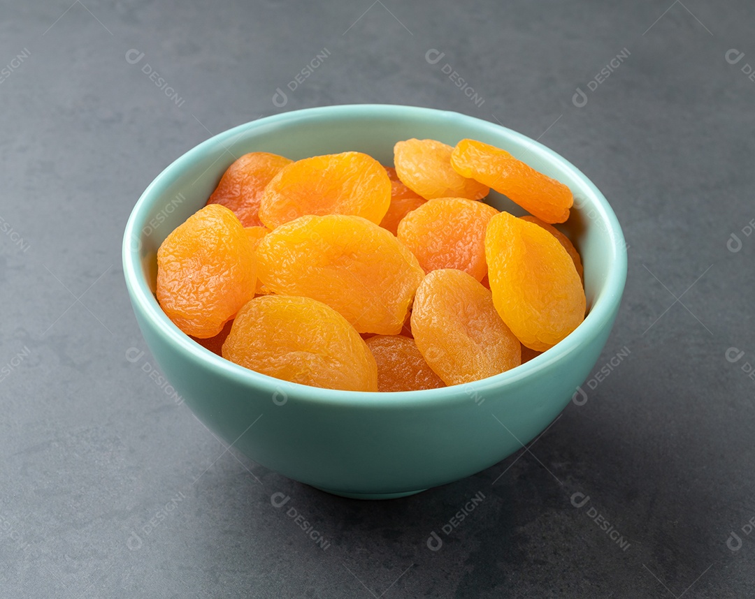 Damascos secos em uma tigela sobre fundo de pedra.