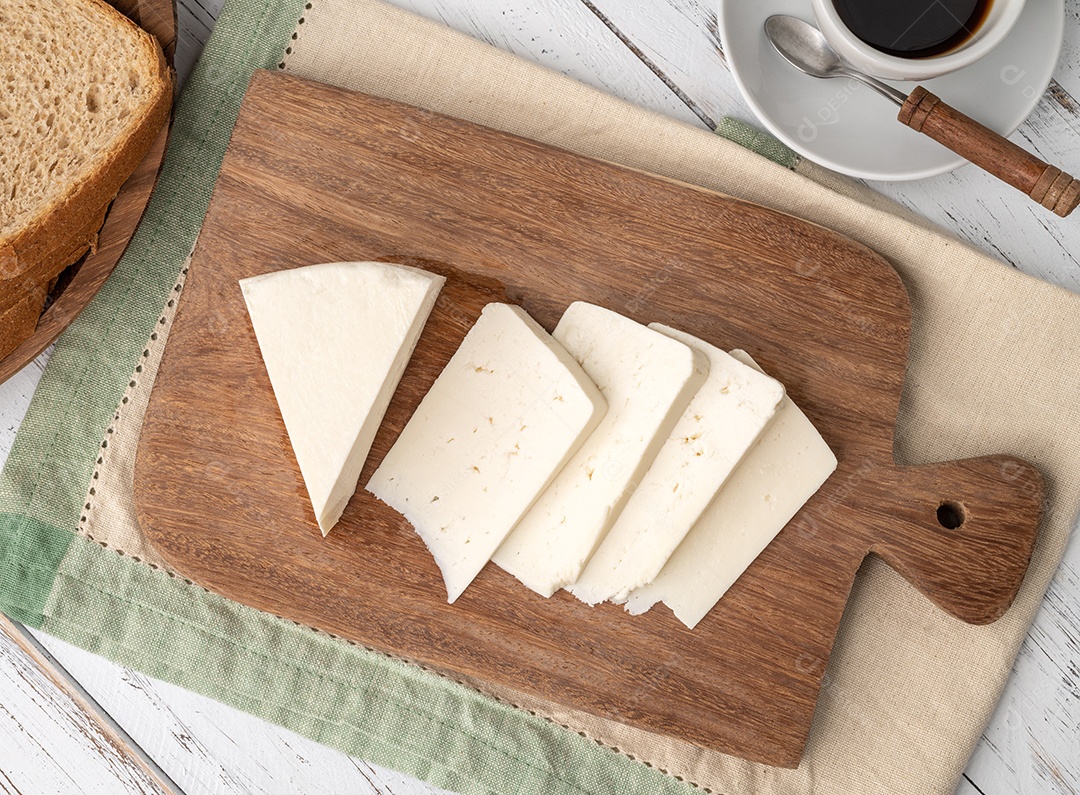 Queijo Canastra fresco artesanal com pão sobre tábua de madeira.