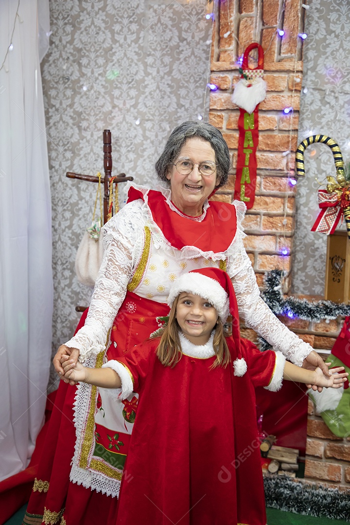 Vó tirando fotografia com sua neta celebrando natal ceia
