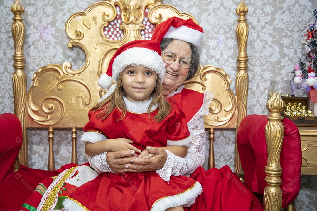 Vó tirando fotografia com sua neta celebrando natal ceia