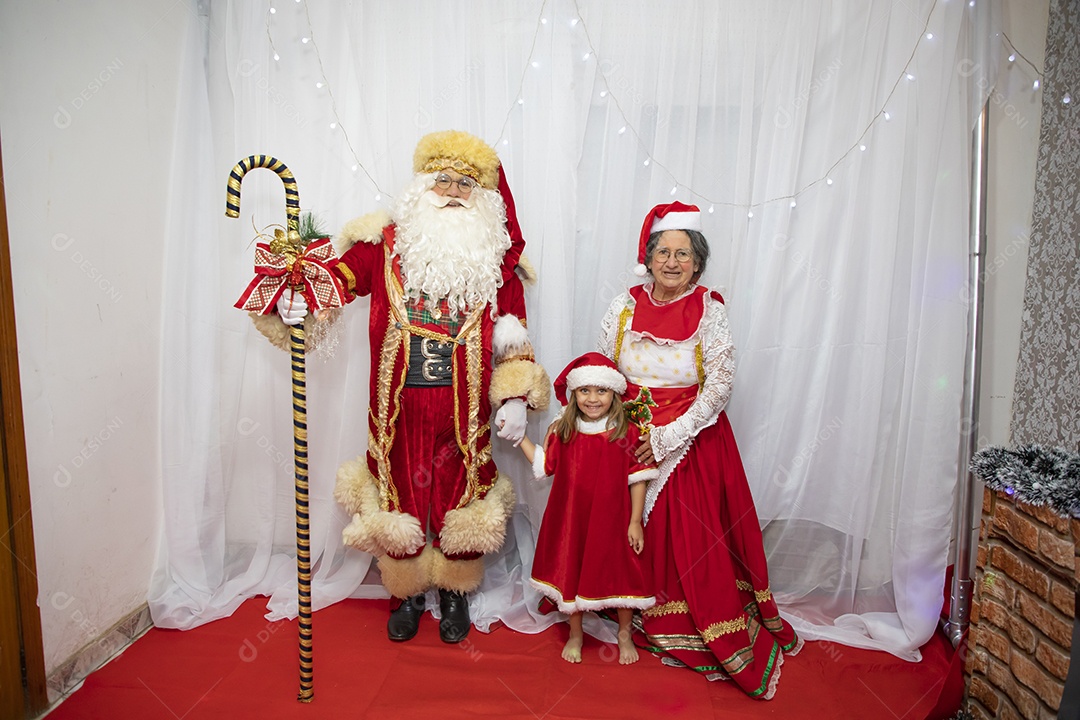 Vó tirando fotografia com sua neta e Papai Noel celebrando natal ceia
