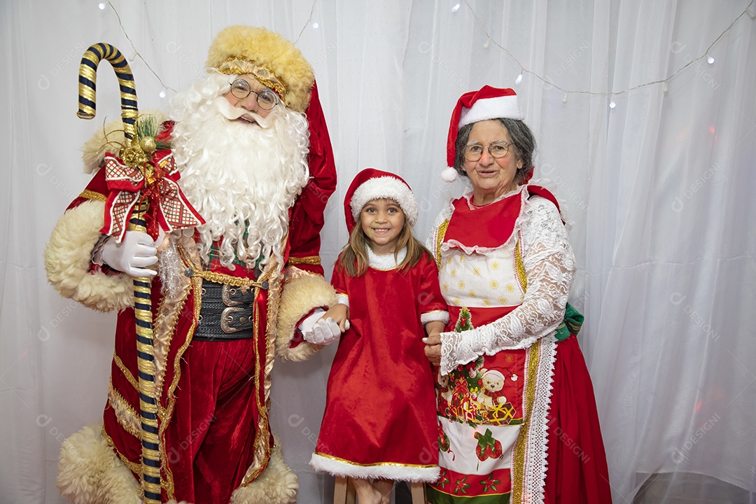 Granny taking a picture with her granddaughter and Santa Claus celebrating christmas supper