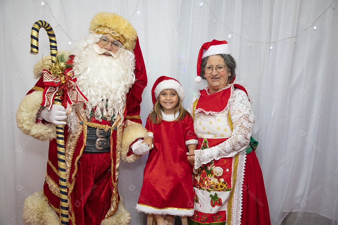 Vó tirando fotografia com sua neta e Papai Noel celebrando natal ceia
