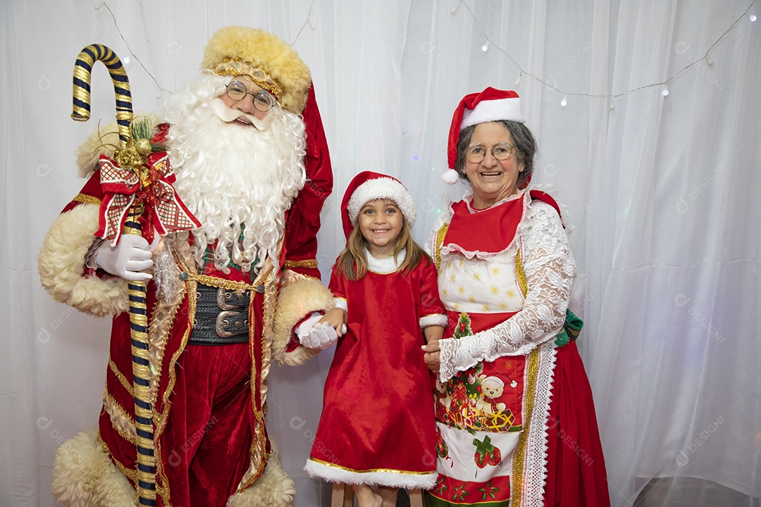 Vó tirando fotografia com sua neta e Papai Noel celebrando natal ceia