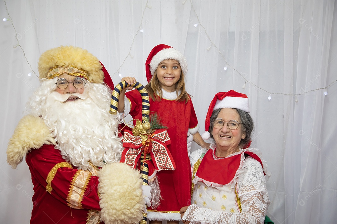 Vó tirando fotografia com sua neta e Papai Noel celebrando natal ceia
