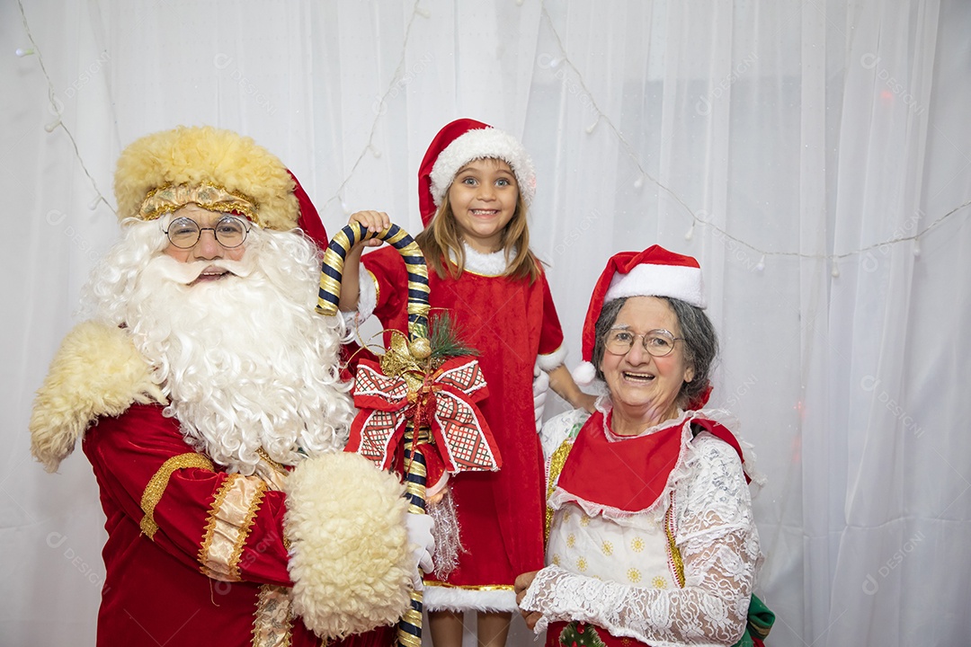Vó tirando fotografia com sua neta e Papai Noel celebrando natal ceia