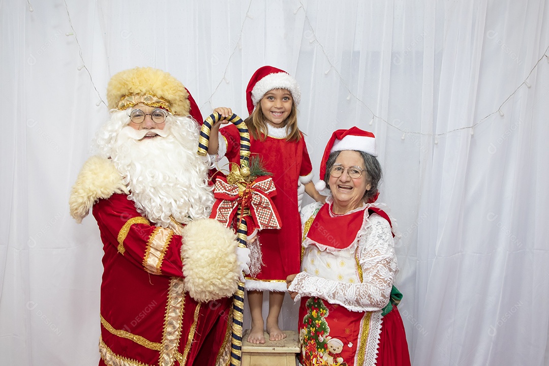 Vó tirando fotografia com sua neta e Papai Noel celebrando natal ceia