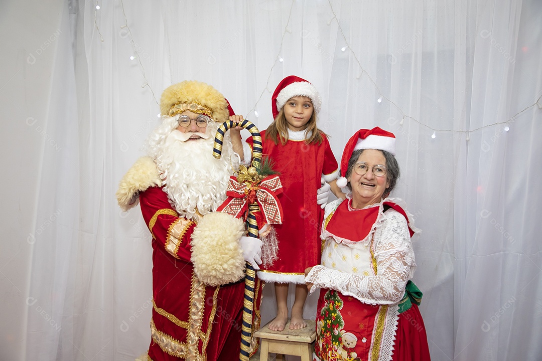 Vó tirando fotografia com sua neta e Papai Noel celebrando natal ceia