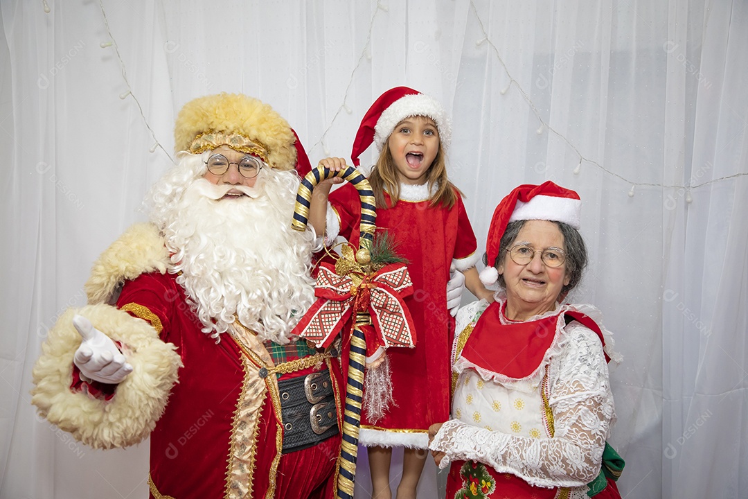 Vó tirando fotografia com sua neta e Papai Noel celebrando natal ceia