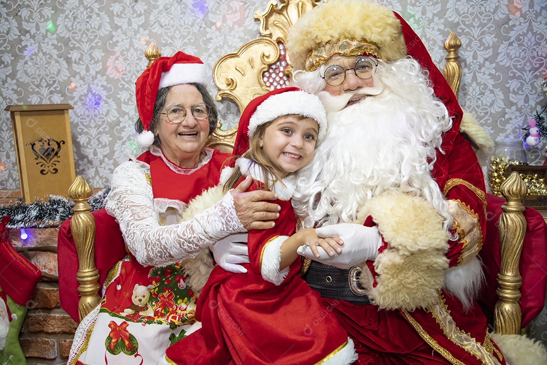 Vó tirando fotografia com sua neta e Papai Noel celebrando natal ceia