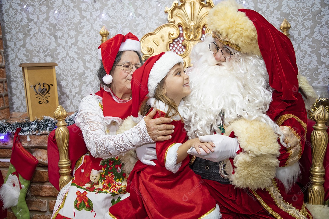 Vó tirando fotografia com sua neta e Papai Noel celebrando natal ceia