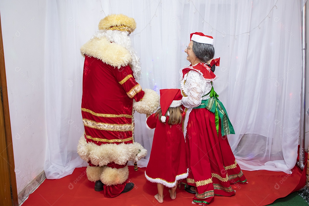 Vó tirando fotografia com sua neta e Papai Noel celebrando natal ceia