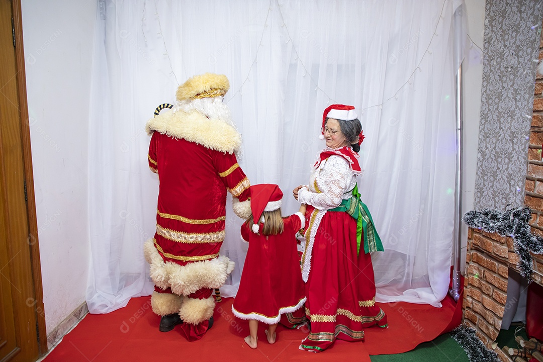 Vó tirando fotografia com sua neta e Papai Noel celebrando natal ceia