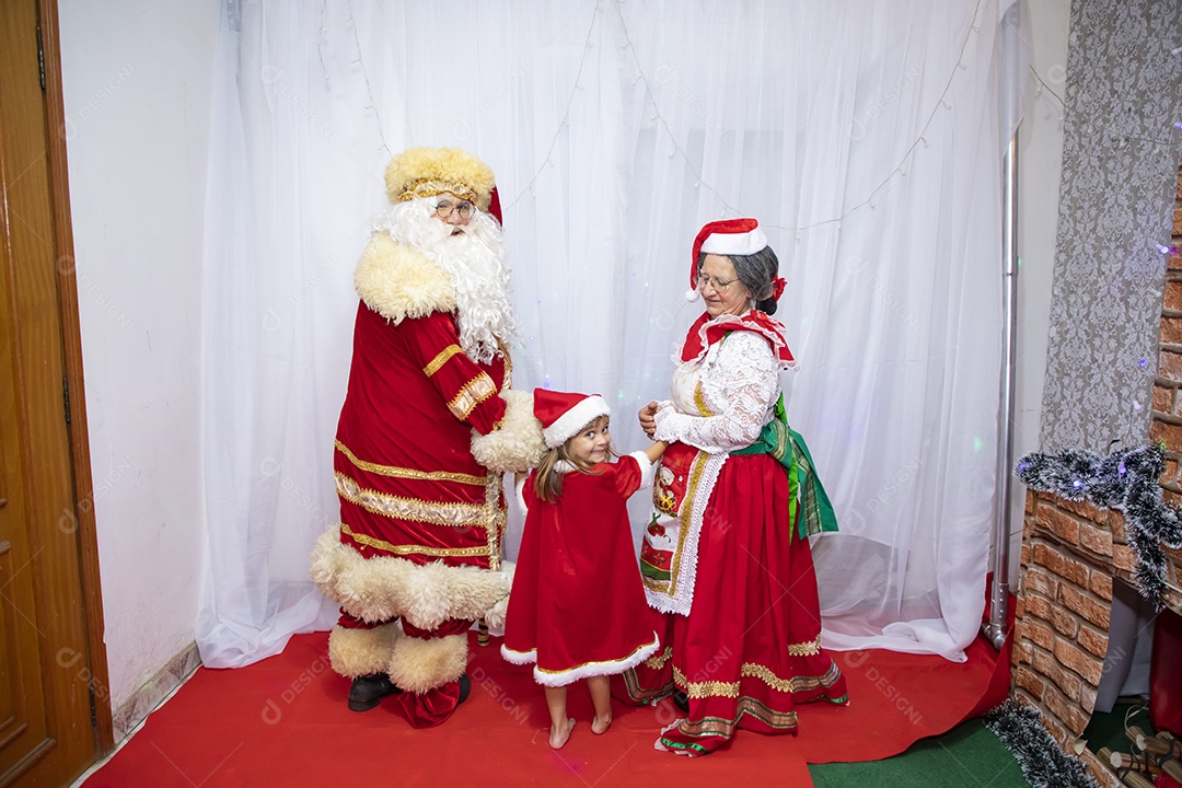 Vó tirando fotografia com sua neta e Papai Noel celebrando natal ceia