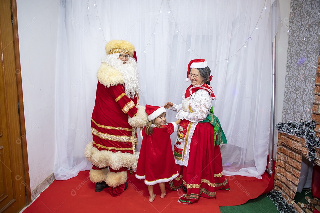 Vó tirando fotografia com sua neta e Papai Noel celebrando natal ceia