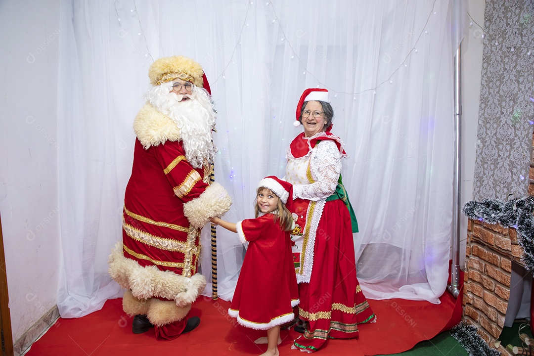 Vó tirando fotografia com sua neta e Papai Noel celebrando natal ceia