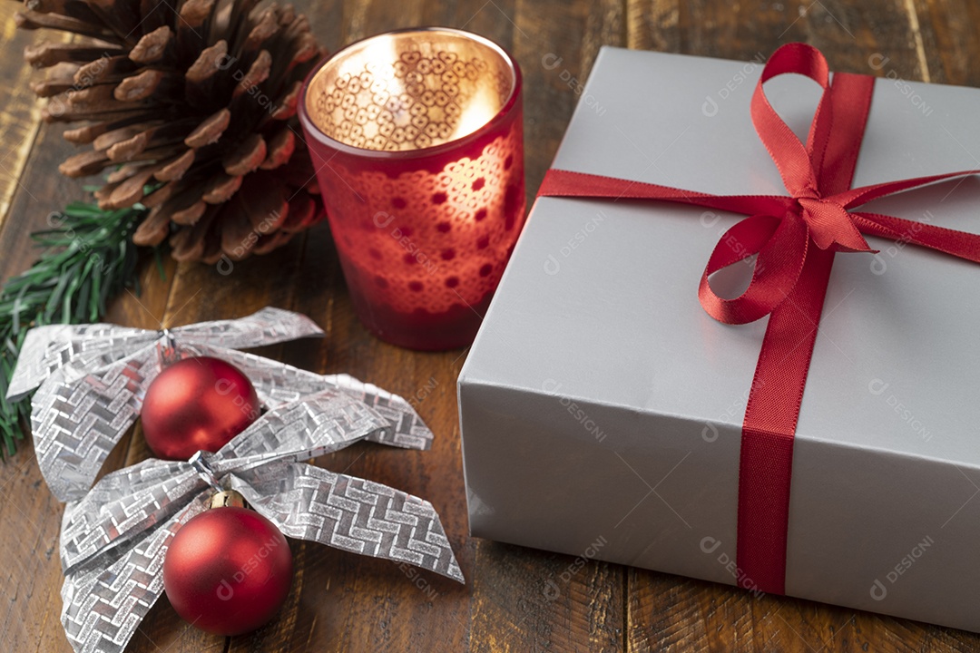 Caixa de presente, pinha, vela, bola de natal e arco sobre a mesa de madeira.