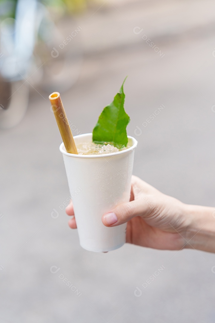 Mão segurando o copo de papel de bebida à base de ervas com pétala de lótus e chá