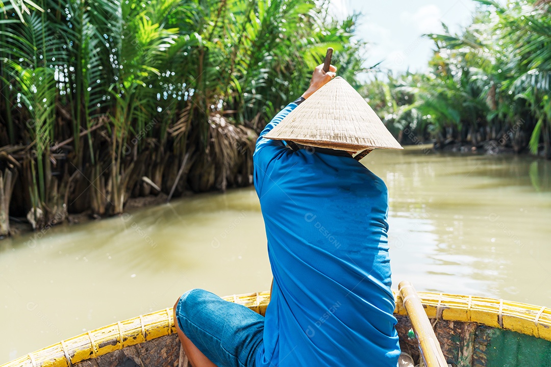 Homem remando um barco de cesta, ao longo da floresta do rio coco