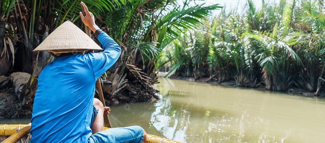 Homem remando um barco de cesta, ao longo da floresta do rio coco