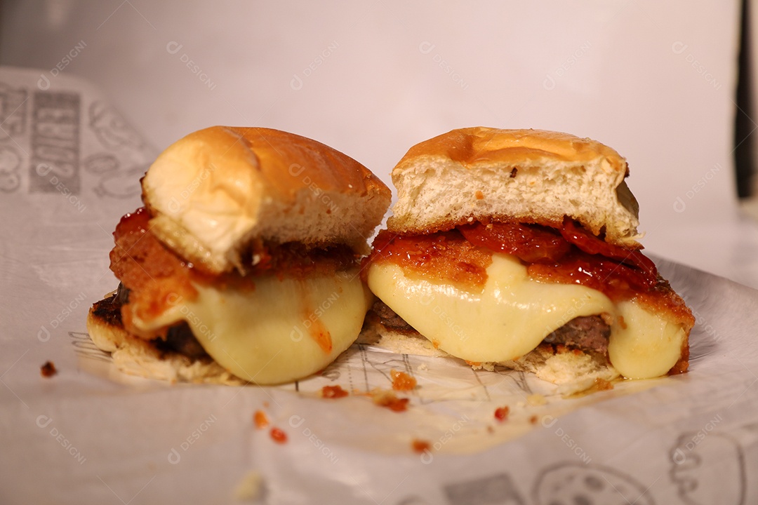 Hamburguer cortado no meio sendo servidos em hamburgueria em fundo branco.