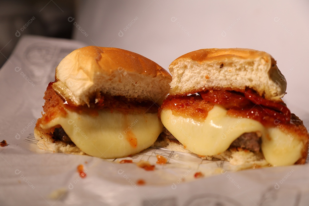 Hamburguer cortado no meio sendo servidos em hamburgueria em fundo branco.