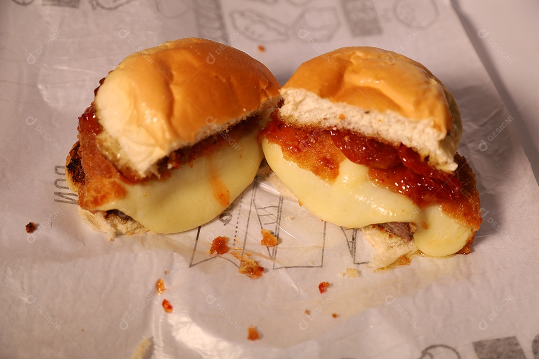 Hamburguer cortado no meio sendo servidos em hamburgueria em fundo branco.