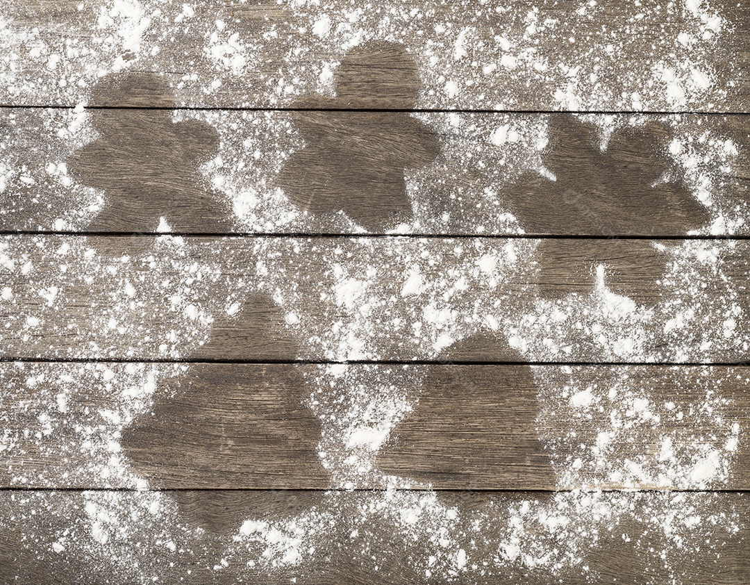 Formas negativas tradicionais de gengibre na farinha sobre a mesa de madeira.