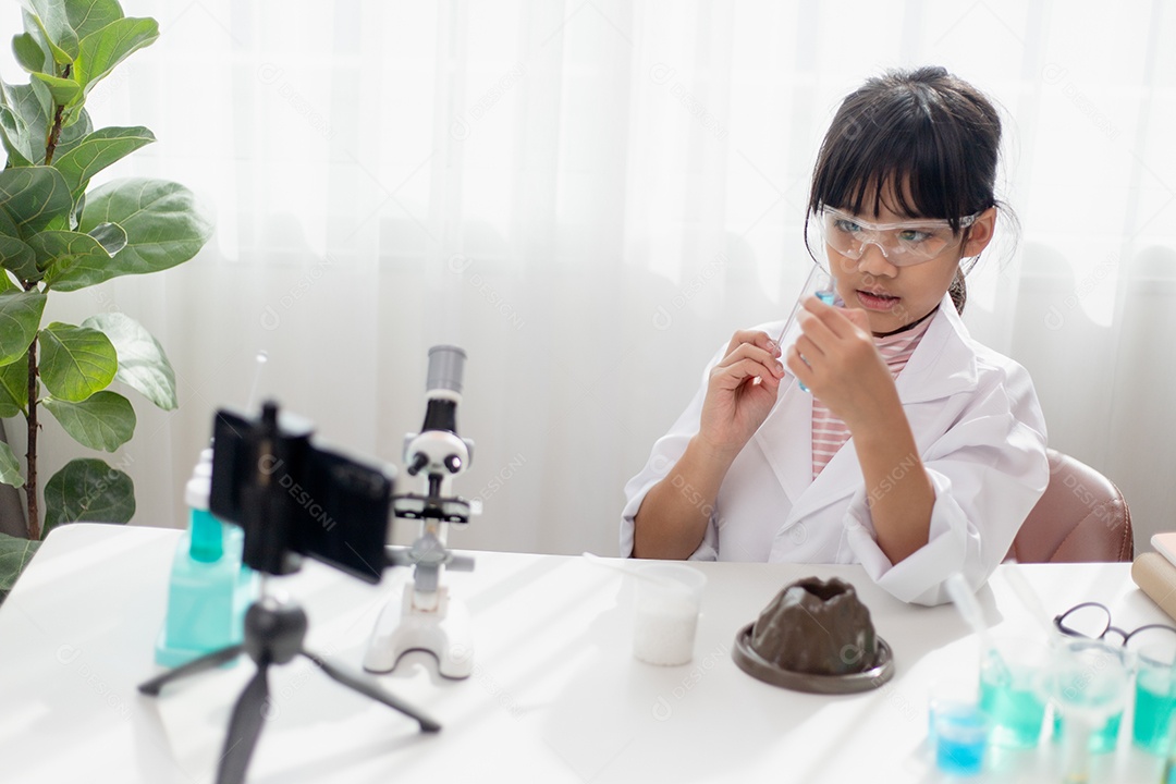Menina da escola asiática fazendo experimentos de química fáceis e gravando