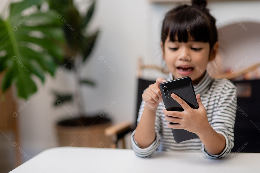 Menina bonito usa o smartphone ao sentar-se no sofá