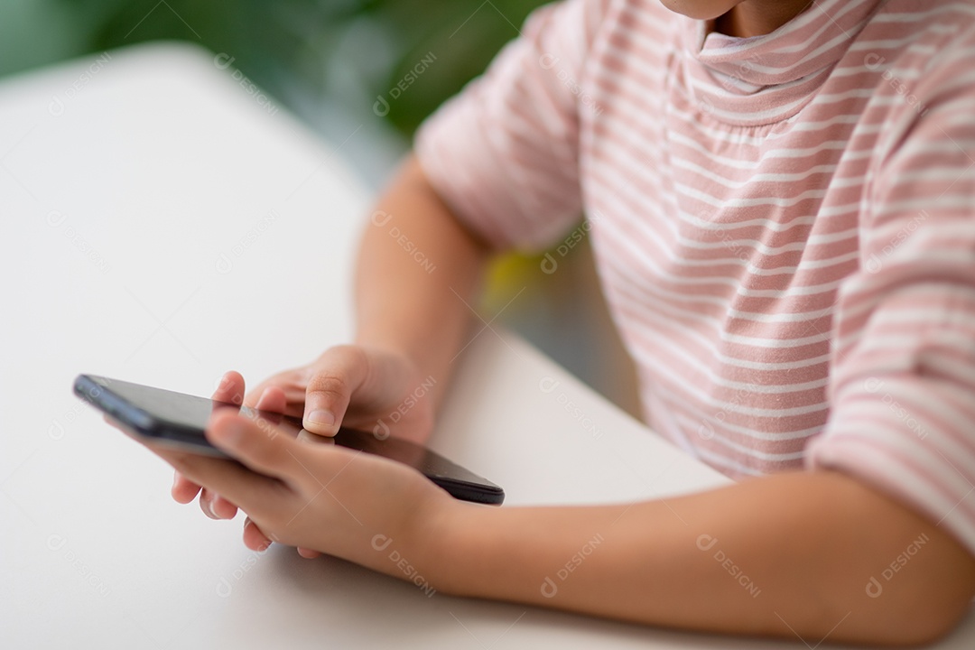 Menina bonito usa o smartphone ao sentar-se no sofá