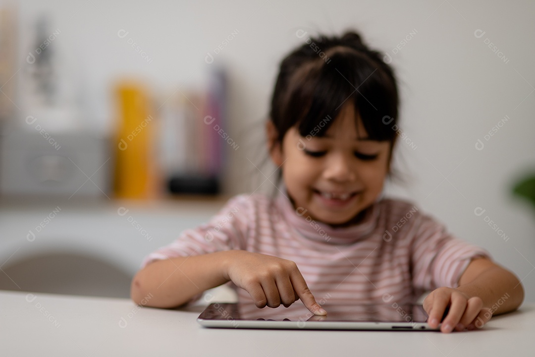 Menina bonita asiática tocando a tela do tablet digital em cima da mesa