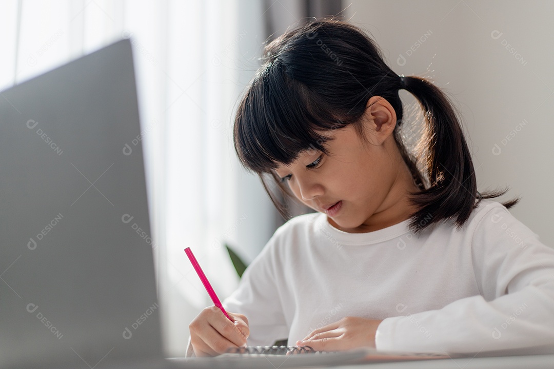 Aluna asiática fazendo sua lição de casa com o laptop em casa.