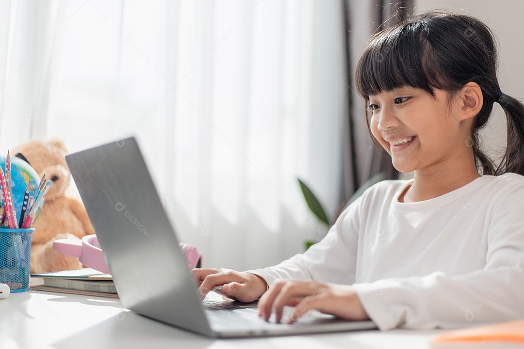 Aluna asiática fazendo sua lição de casa com o laptop em casa.