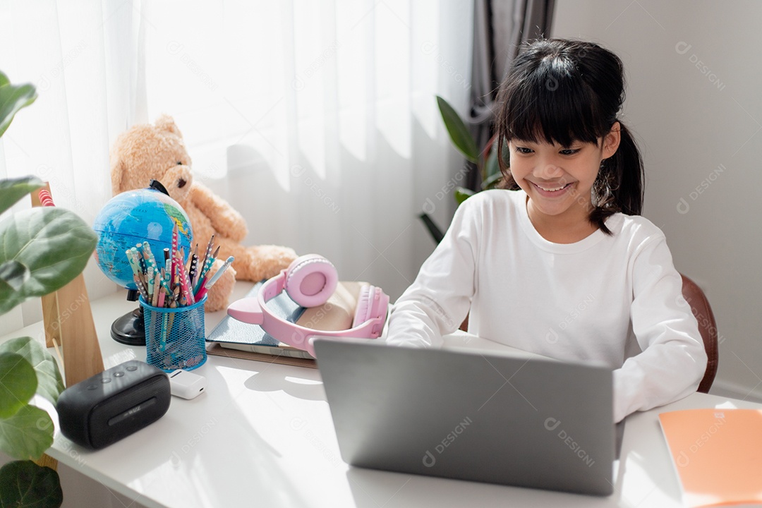 Aluna asiática fazendo sua lição de casa com o laptop em casa.