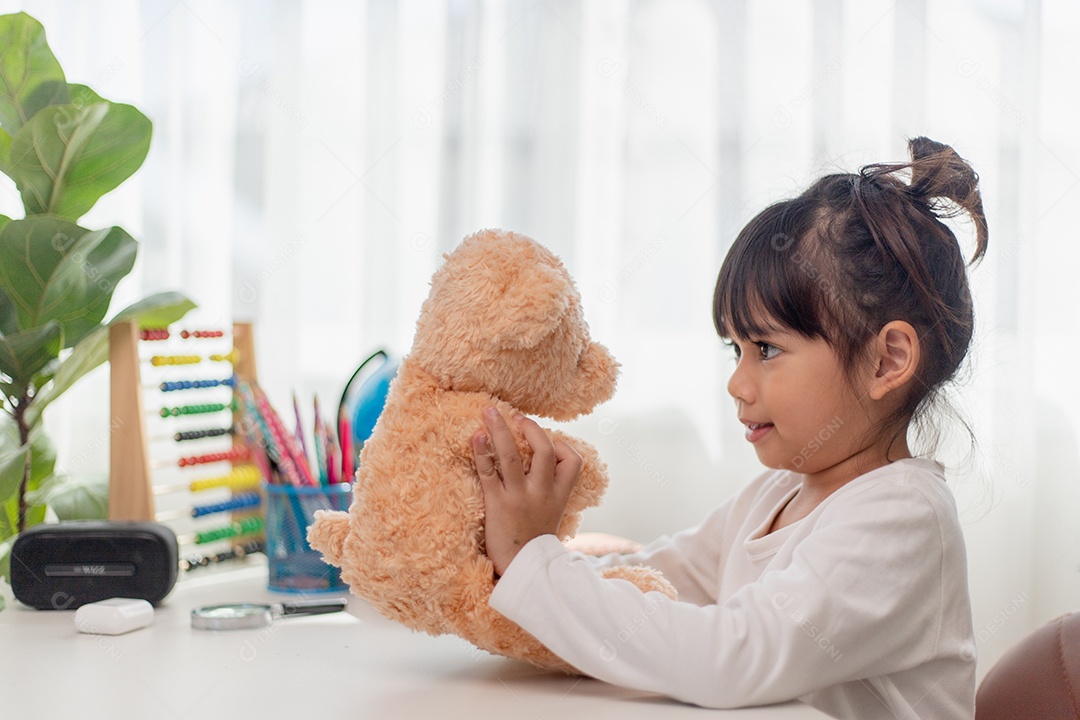 Criança brincando com ursinho de pelúcia. Menina asiática abraçando seu favorito.