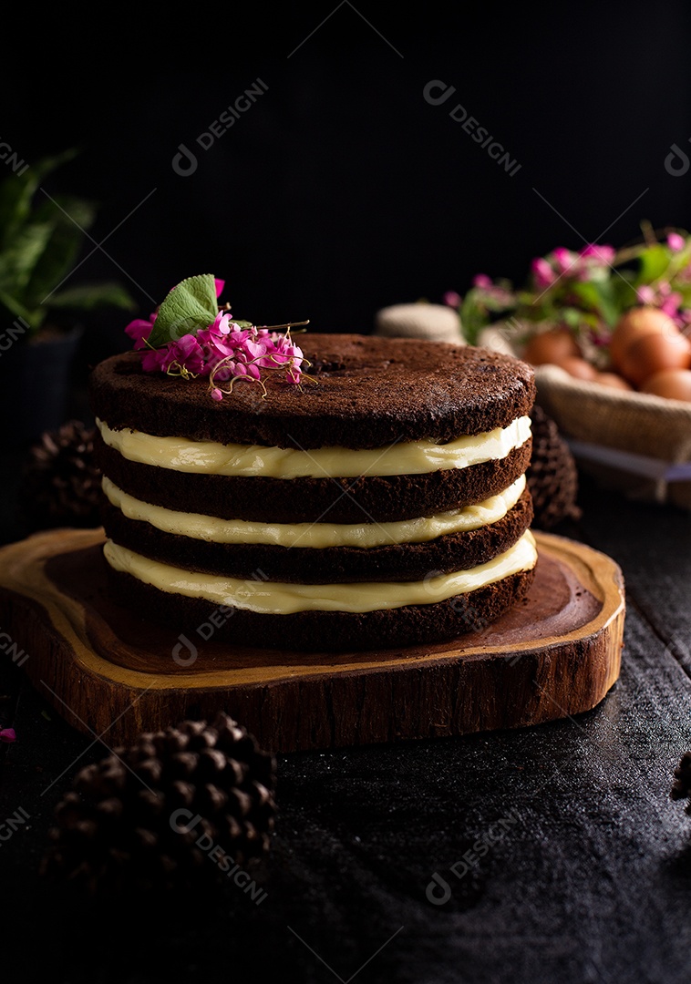 Bolo confeitado de chocolate fatiado sobre tabua de madeira