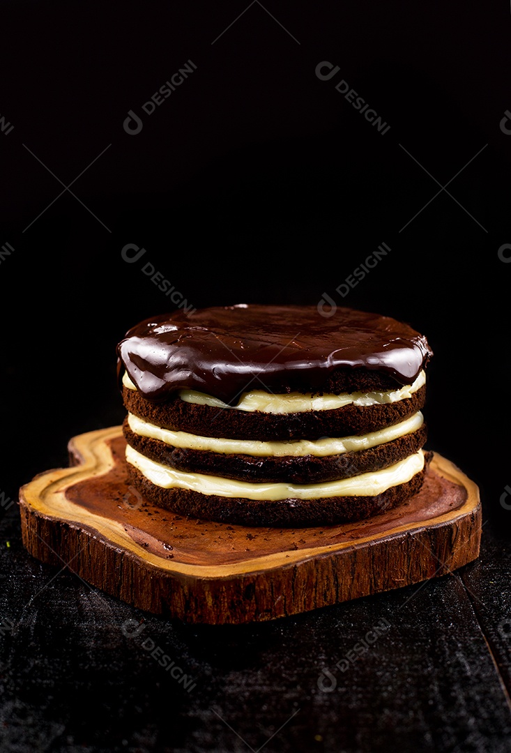 Bolo confeitado de chocolate sobre tabua de madeira