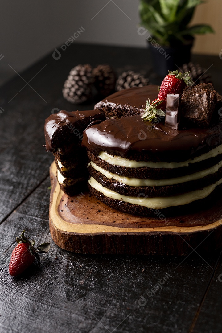 Bolo confeitado de chocolate sobre tabua de madeira