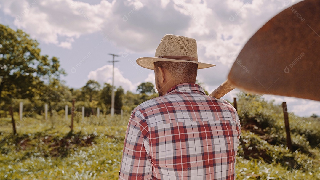 Retrato de jovem de camisa casual segurando sua enxada na fazenda. Ferramenta de fazenda. homem latino.