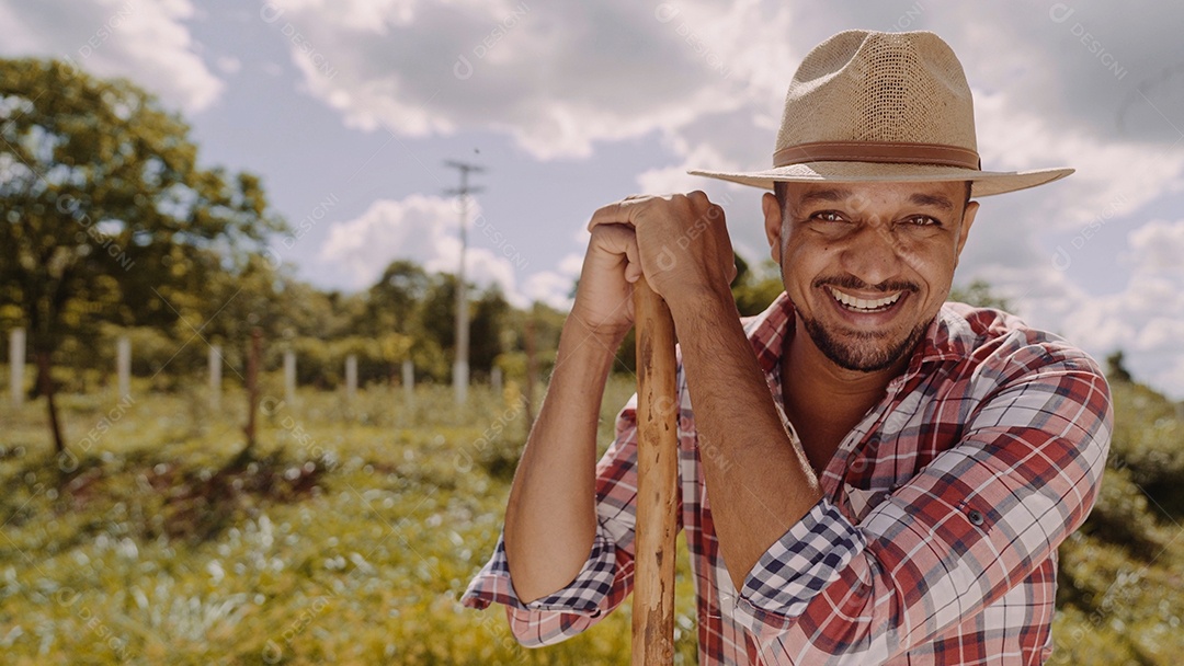 Retrato de jovem de camisa casual segurando sua enxada na fazenda. Ferramenta de fazenda. homem latino.