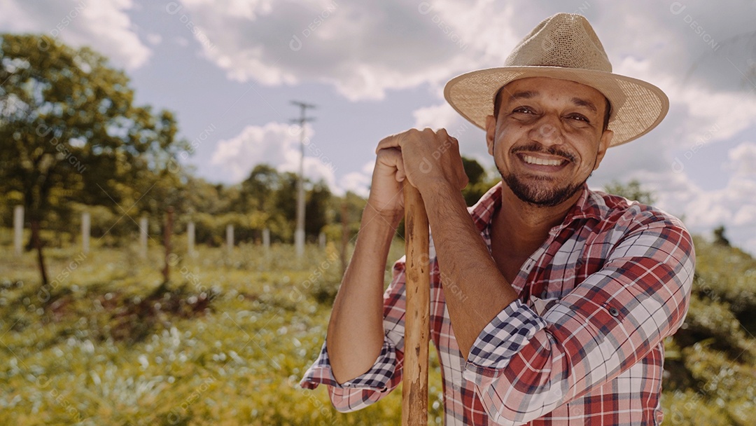 Retrato de jovem de camisa casual segurando sua enxada na fazenda. Ferramenta de fazenda. homem latino.