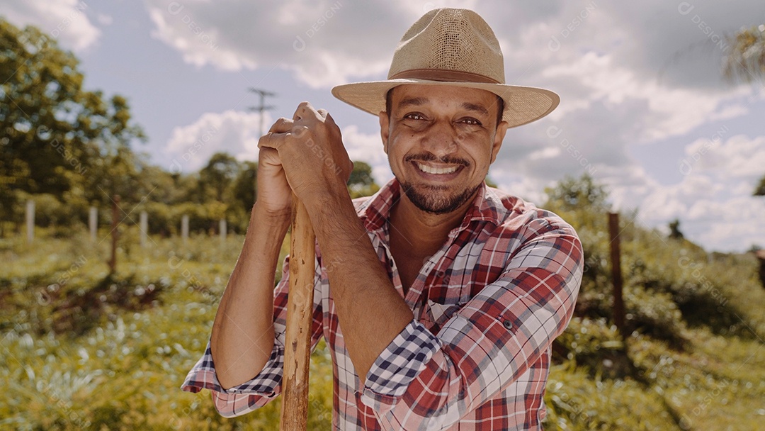 Retrato de jovem de camisa casual segurando sua enxada na fazenda. Ferramenta de fazenda. homem latino.