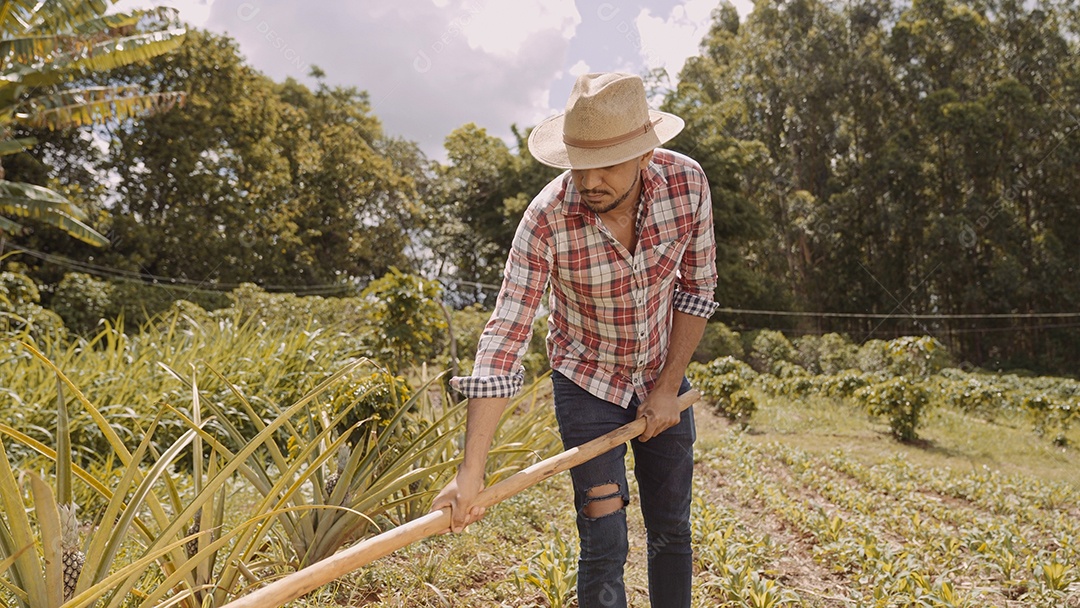Retrato de jovem de camisa casual segurando sua enxada na fazenda. Ferramenta de fazenda. homem latino.