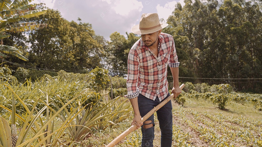 Retrato de jovem de camisa casual segurando sua enxada na fazenda. Ferramenta de fazenda. homem latino.