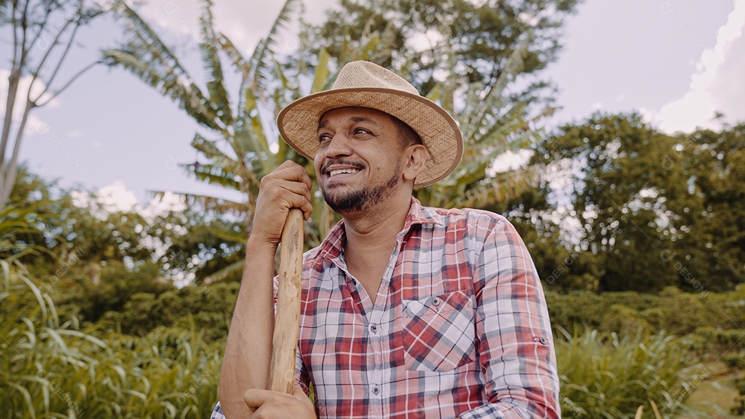 Retrato de jovem de camisa casual segurando sua enxada na fazenda. Ferramenta de fazenda. homem latino.