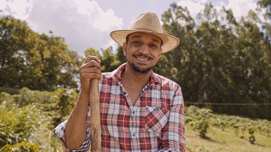 Retrato de jovem de camisa casual segurando sua enxada na fazenda. Ferramenta de fazenda. homem latino.