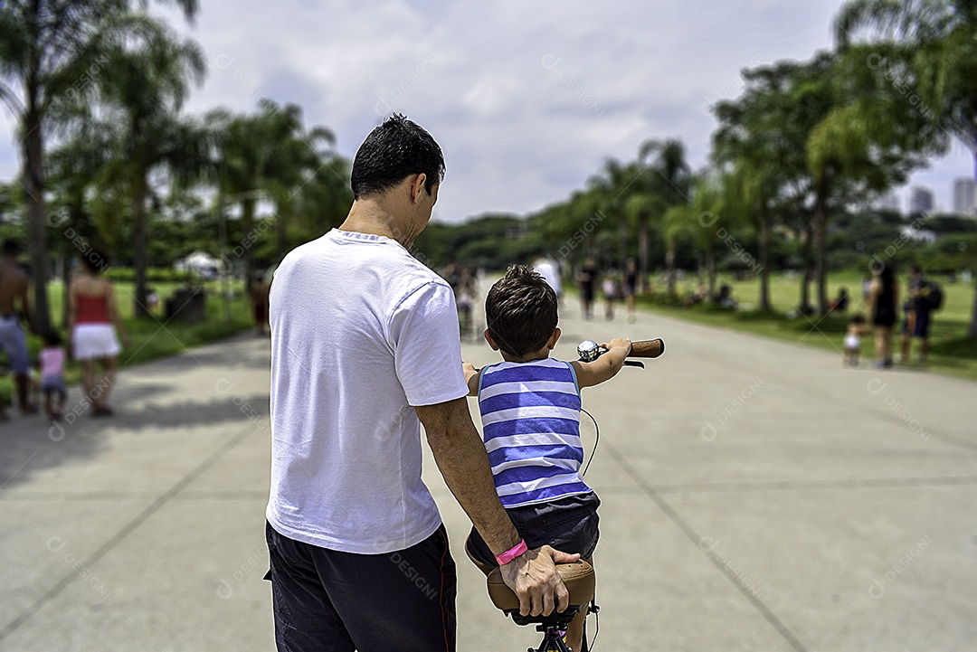 Pai e filho andando de bicicleta no parque.